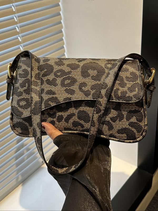 Brown and beige crossbody bag with leopard print pattern and gold hardware, held by a hand.