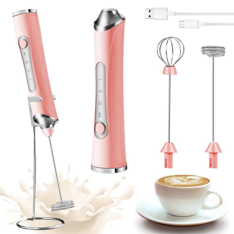 Pink electric milk frother with attachments and charging cable, beside cup of coffee.